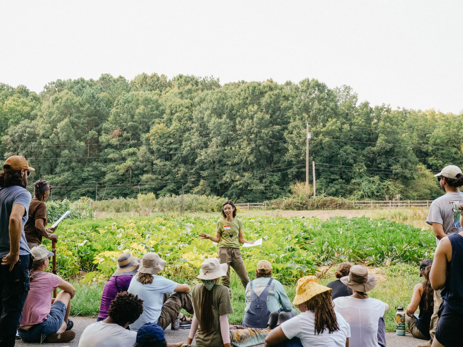 Woman in a farm field leading an educational session for a group of farmers