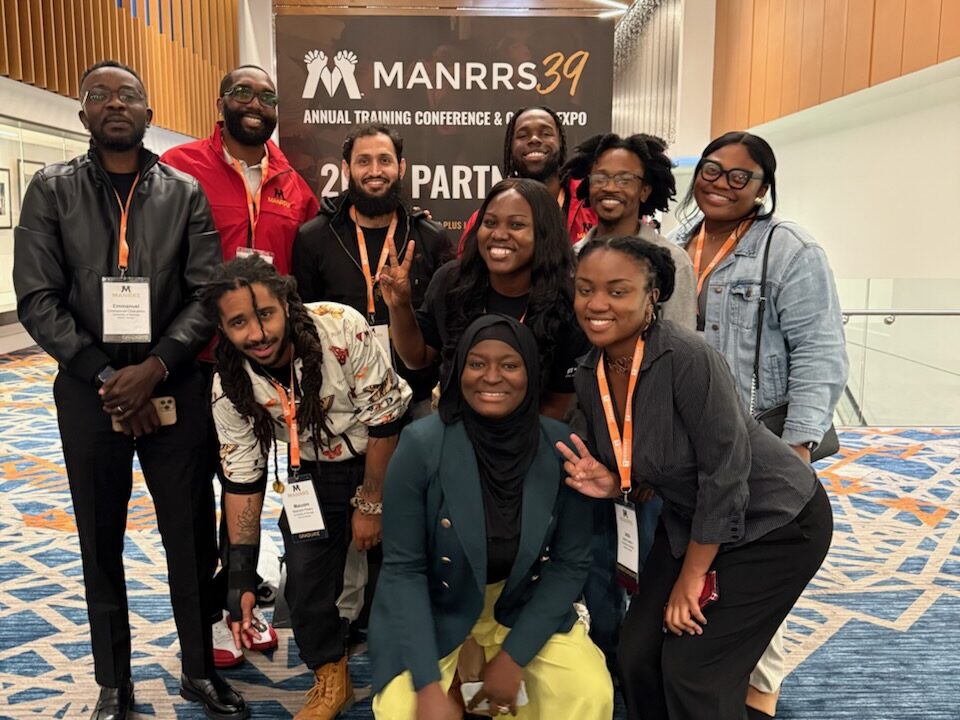 A group of people posing in front of a sign for a MANRRS conference