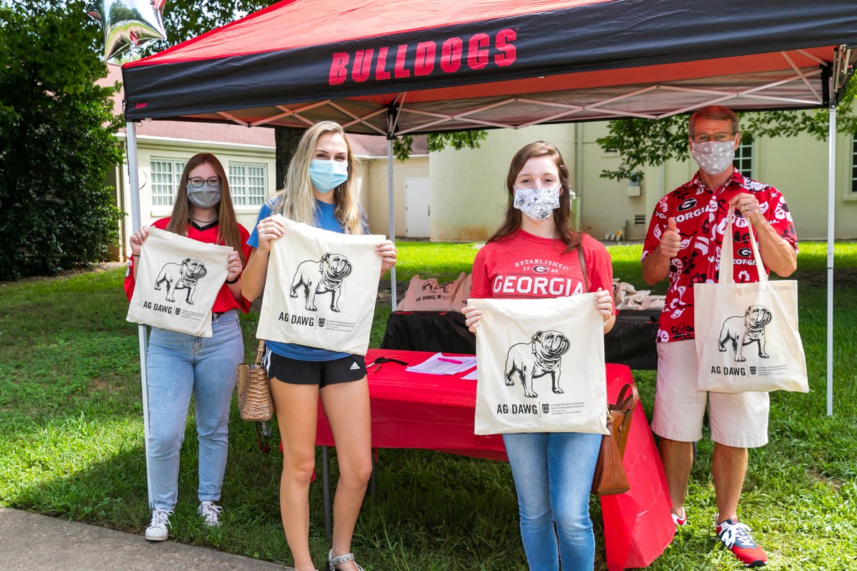 Katie Fife (far left) and Doug Bailey, assistant dean for academic affairs, (far left) hand out Ag Dawg swag bags at Ag Dawg Kickoff.