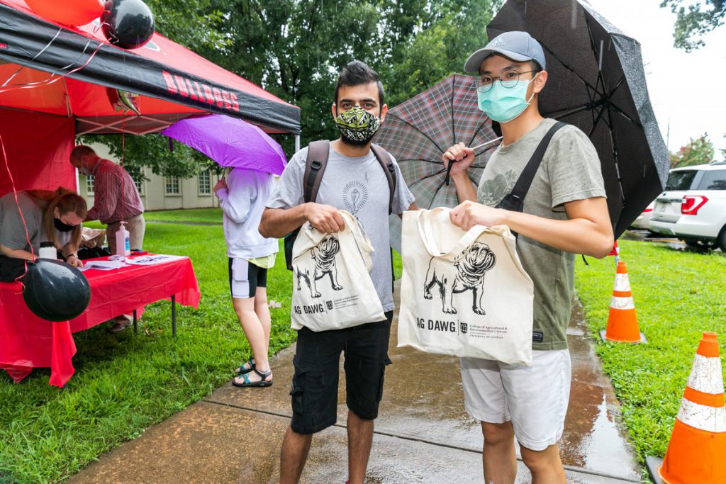 Two students brave the rain to pick up their Ag Dawg swag bag.