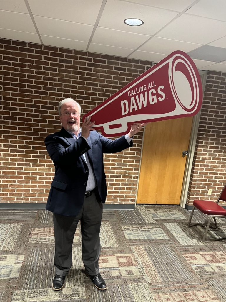 Tim Miller holding a Calling All Dawgs megaphone cut out