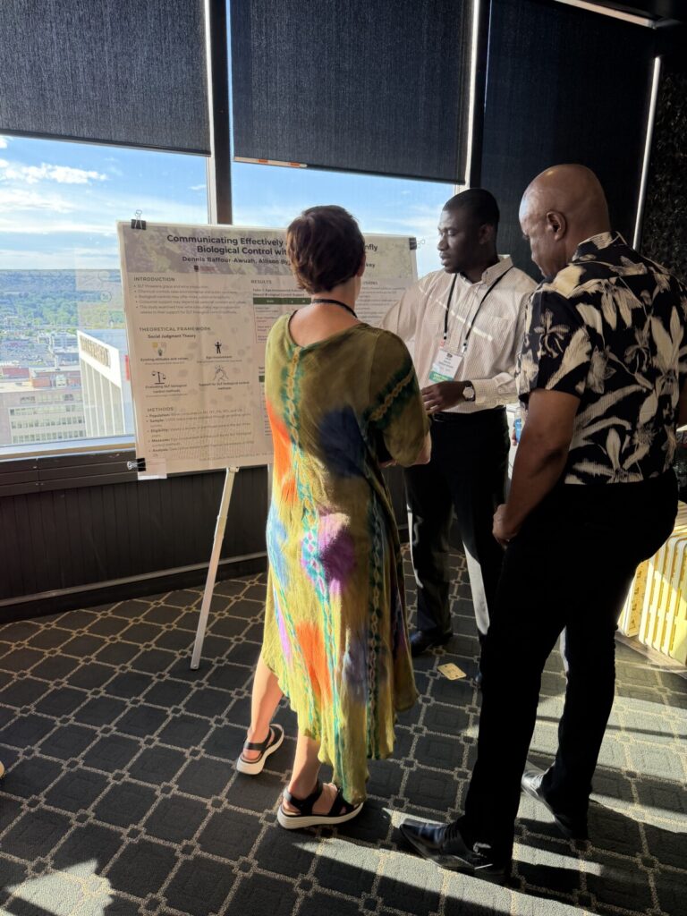 Baffour presenting poster to two conference attendees