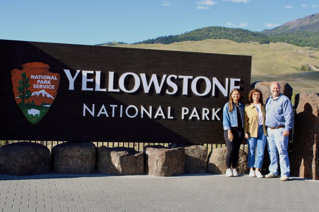 Gracie poses with her parents for a picture at Yellowstone, Montana