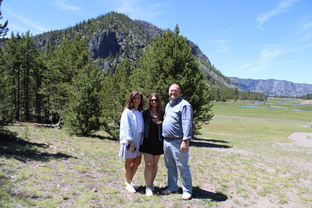 Gracie poses with her parents for a picture at Yellowstone National Park, Montana